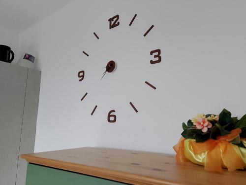 a clock on a white wall with a vase of flowers at Casa Olivella in Bardolino
