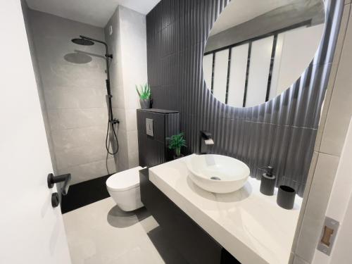 łazienka z umywalką, toaletą i lustrem w obiekcie Appartement Étoilé, Plage, Parking, WiFi, Calme w mieście La Grande-Motte