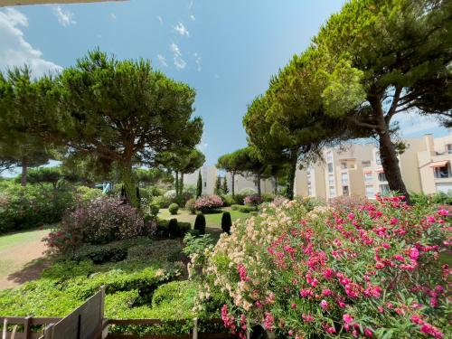 un jardin avec des fleurs et des arbres et un bâtiment dans l'établissement Appartement Étoilé, Plage, Parking, WiFi, Calme, à La Grande Motte