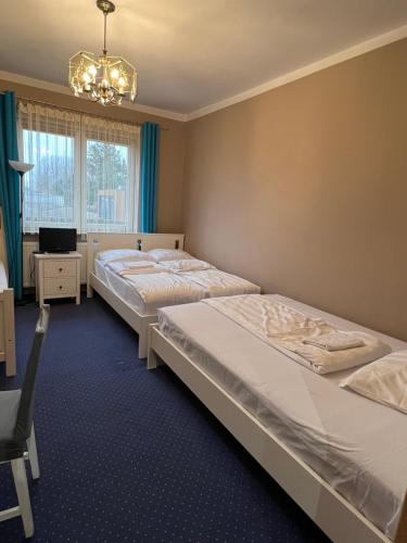 a bedroom with two beds and a chandelier at Noclegi AirportPark in Pyrzowice