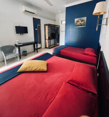a bedroom with two beds with red sheets and a piano at Jas Telaga Inn Homestay in Teluk Mas