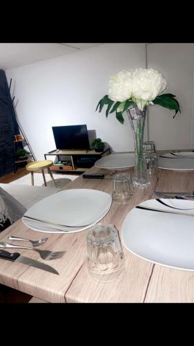 une table avec des assiettes blanches et un vase de fleurs dans l'établissement Le Cocon de la Bastille - DaLoc, à Grenoble