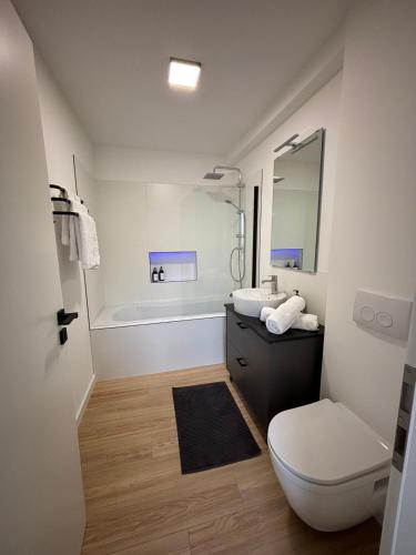 a bathroom with a toilet and a sink and a tub at Appartement Hoang in Ans