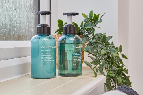 two bottles of soap sitting on a counter with a plant at Wilford Place in Nottingham