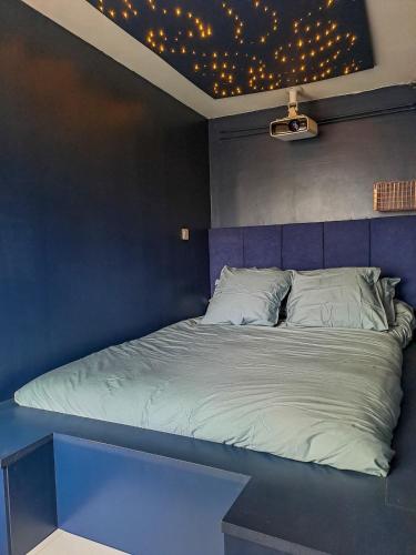 une chambre avec un lit avec un mur bleu dans l'établissement Vannes - L'étoilé, parking et linge inclus, à Vannes