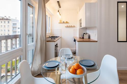 une salle à manger avec une table en verre et des chaises blanches dans l'établissement Amazing deal - Central Location near the metro, Modern amenities and style, à Paris