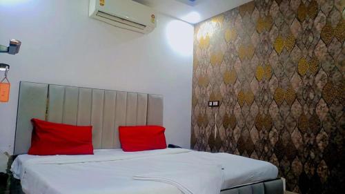 a bedroom with a bed with two red pillows at Hotel VCR INN in New Delhi