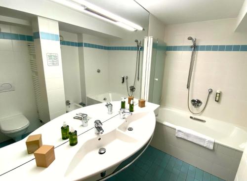 a bathroom with a sink and a tub and a toilet at Hotel-Restaurant Batzenhäusl in Innsbruck
