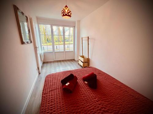 une chambre avec un lit rouge et une grande fenêtre dans l'établissement Niki, belle vue sur le Loiret, à Saint-Pryvé-Saint-Mesmin