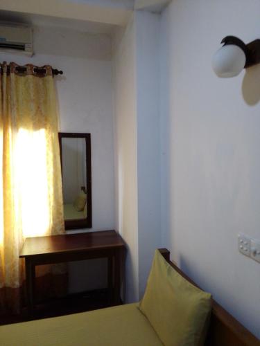 a bedroom with a bed and a mirror and a window at Pravindi Guest Home in Mirissa