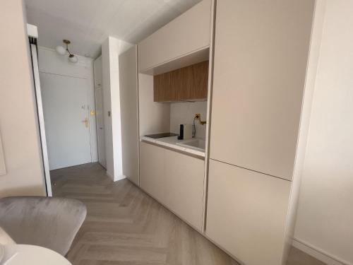 une cuisine avec des armoires blanches et un plancher en bois dans l'établissement Appartement Étoilé, Clim, Plage, Parking, Terrasse, à La Grande Motte
