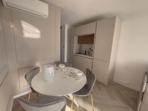 - une table et des chaises blanches dans une petite cuisine dans l'établissement Appartement Étoilé, Clim, Plage, Parking, Terrasse, à La Grande Motte