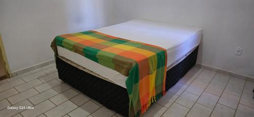 a bed with a colorful blanket on top of it at Apartamento Guriri Verão in São Mateus