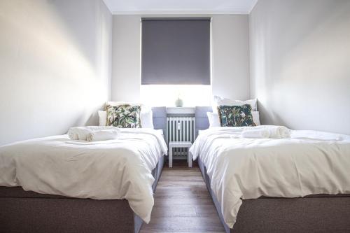 two beds in a room with white sheets and a window at EssenFusion Wasserturm - Innenstadt nahe der Messe, SmartTV, Nespresso, Fully Kitchen in Essen