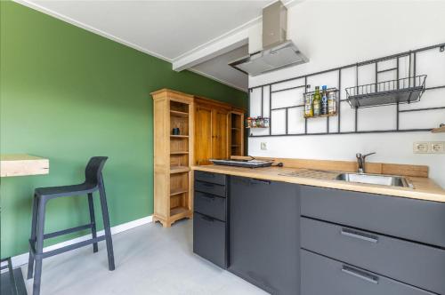 a kitchen with green walls and a sink and a chair at Grandioso Appartement - Studio in Castricum