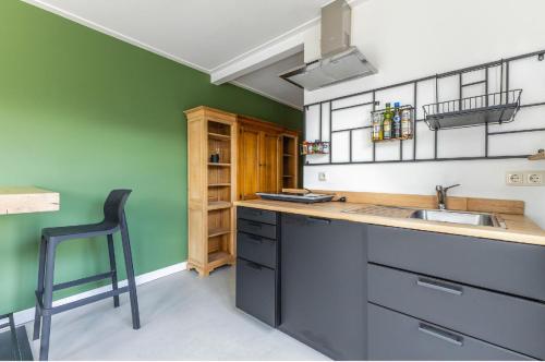 a kitchen with green walls and a sink and a chair at Grandioso Appartement - Studio in Castricum