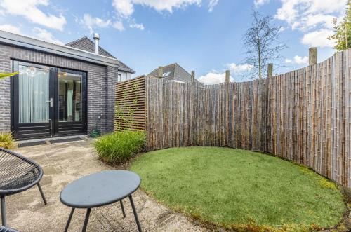 a backyard with a fence and a table and chairs at Grandioso Appartement - Studio in Castricum