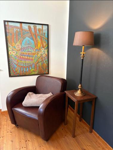 a brown leather chair next to a table with a lamp at Ferienwohnung EG AusZeit in Bad Bertrich