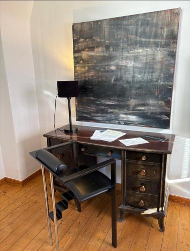 a desk with a chair next to a painting on a wall at Ferienwohnung EG AusZeit in Bad Bertrich