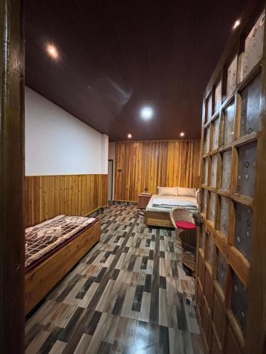 two beds in a room with wooden walls at Payun Homestay in Mirik