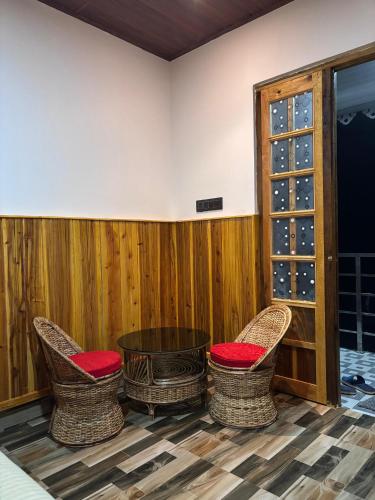 a room with two chairs and a table with wine glasses at Payun Homestay in Mirik
