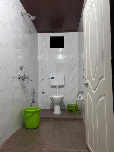 a bathroom with a toilet and a green bucket at Payun Homestay in Mirik