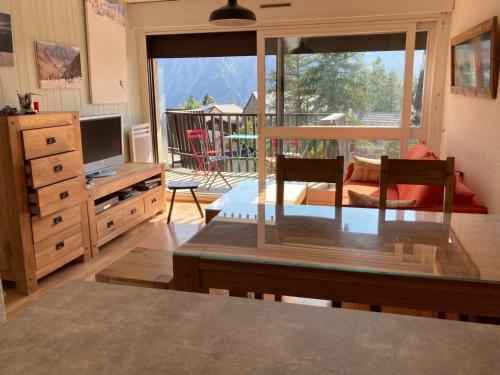 un salon avec une télévision et une table avec une table dans l'établissement Appartement accueillant au pied des pistes avec balcon et cuisine équipée - FR-1-516-21, à Les Deux Alpes