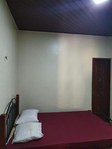 a bedroom with a bed with a red blanket and a white wall at Aconchego do Viana in Belém