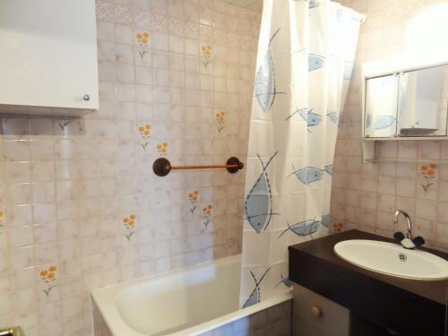 une salle de bain avec un lavabo et un rideau de douche dans l'établissement À deux pas des pistes et de la crèche, appartement cosy avec terrasse, parking et casier à ski. - FR-1-516-66, à Les Deux Alpes