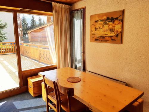 - une table et des chaises en bois dans une chambre avec fenêtre dans l'établissement À deux pas des pistes et de la crèche, appartement cosy avec terrasse, parking et casier à ski. - FR-1-516-66, à Les Deux Alpes