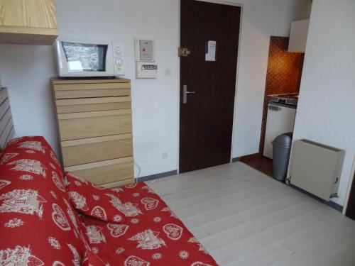 Cette petite chambre comprend un lit rouge et une cuisine. dans l'établissement Studette cosy au pied des pistes, centre des Deux Alpes, pour 2 personnes - FR-1-516-91, à Les Deux Alpes