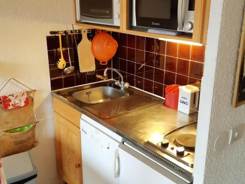 une petite cuisine avec un évier et un micro-ondes dans l'établissement Studio cosy au pied des pistes avec balcon et parking - FR-1-516-103, à Les Deux Alpes