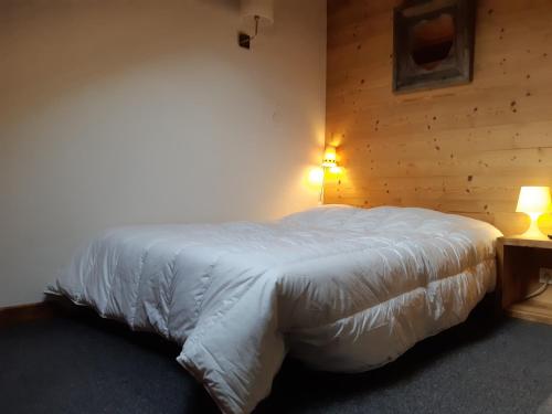 - une chambre avec un lit avec des draps blancs et 2 lampes dans l'établissement Duplex Montagne avec Sauna, Wifi, Parking - FR-1-516-147, à Les Deux Alpes