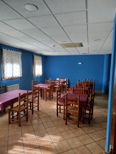 a room with tables and chairs and a blue wall at Hotel Restaurante El CID in Torres de Albarracín