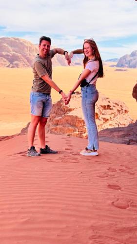 a man and woman holding hands in the desert at Rum Angel Camp in Wadi Rum