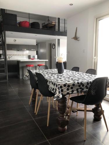 une salle à manger avec une table et des chaises en noir et blanc dans l'établissement Maison contemporaine aux Sables d 'Olonne, à Les Sables-dʼOlonne