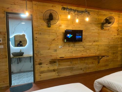 a bedroom with a wooden wall with a tv and a mirror at A Thía homestay in Diện Biên Phủ