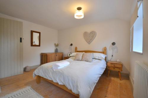 a bedroom with a bed with a heart on the wall at Albie Cottage in Grimston
