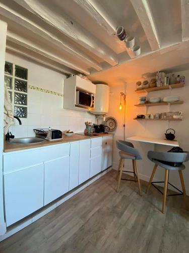 une cuisine avec des armoires blanches et une table et des chaises dans l'établissement Cute studio in Versailles, à Versailles