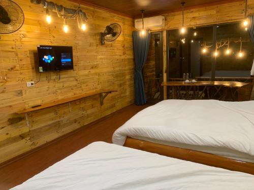 a bedroom with two beds and a tv on a wall at A Thía homestay in Diện Biên Phủ