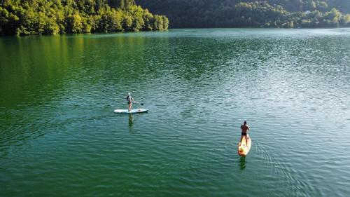 two people are standing on a paddle board in a lake at Sokograd Attic in Šipovo