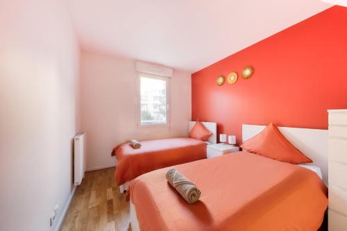 a bedroom with two beds and an orange wall at Terracotta Room - Proche Stade de France & CDG & Paris in Saint-Denis
