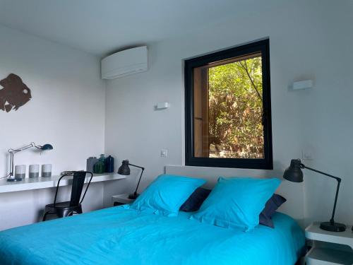 une chambre avec un lit bleu et une fenêtre dans l'établissement La Franqui Vue Mer Exceptionnel, à La Franqui-Plage
