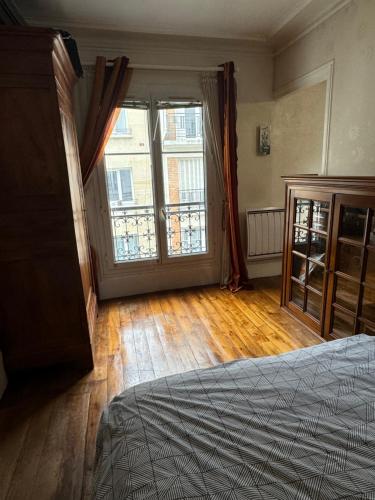 une chambre avec un lit et une grande fenêtre dans l'établissement Joli deux pièces near Eiffel Tower, à Paris