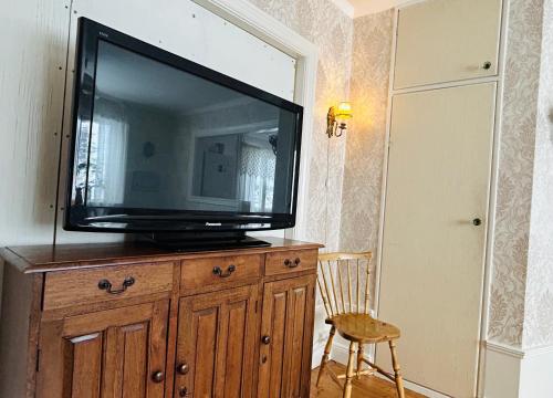 a television on top of a wooden dresser with a chair at Fyra rum och kök i Mellanfjärden in Mellanfjärden