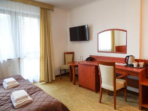a hotel room with a desk and a bed at Hotel Muszyna in Muszyna