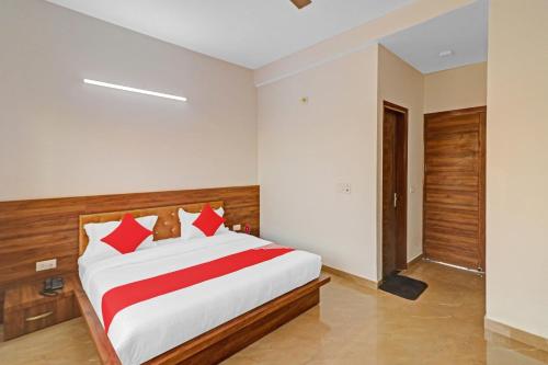 a bedroom with a large white bed with red pillows at Hotel O Safari Inn in Hāpur