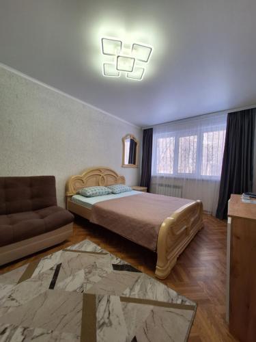 een slaapkamer met een bed en een bank bij квартира in Balqash