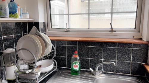 a kitchen sink with a dish drying rack and a bottle of soda at Gravesend Guest Retreat in Gravesend