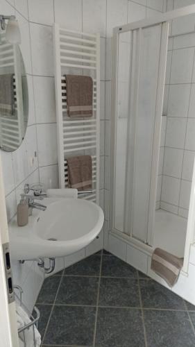 a white bathroom with a sink and a shower at Ferienwohnung Teutoblick in Tecklenburg